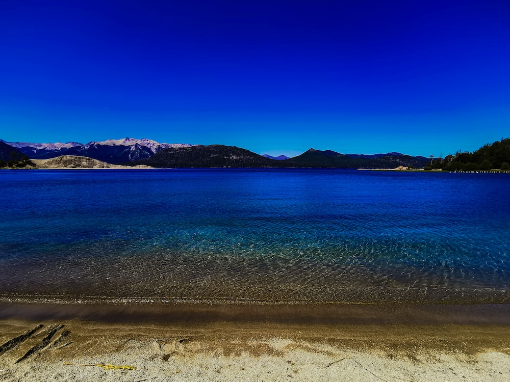 a beach with a body of water and mountains in the background