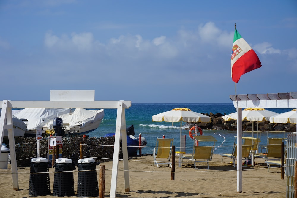 a beach with chairs and umbrellas and a flag
