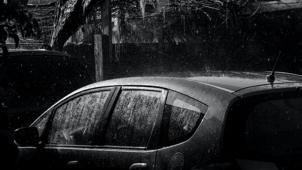 a black and white photo of a car in the rain