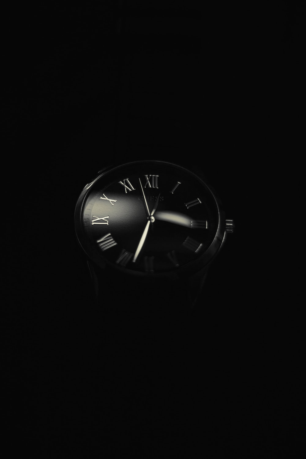 a black and white photo of a clock in the dark