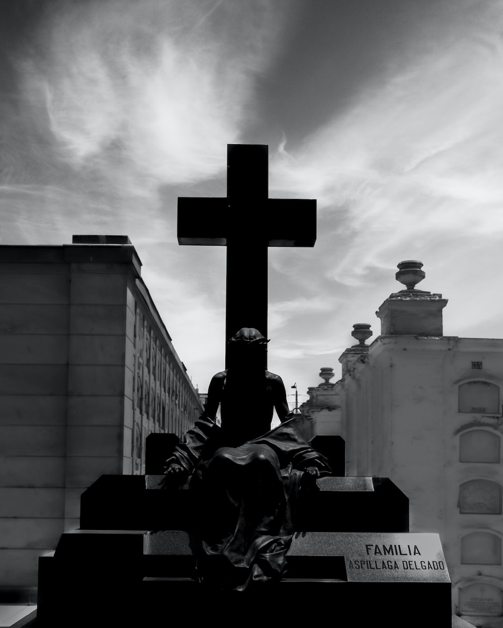 a black and white photo of a person sitting at a cross