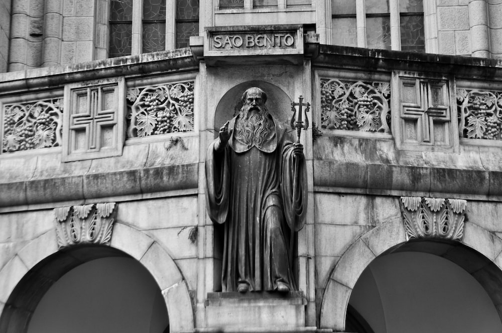 a black and white photo of a statue on a building