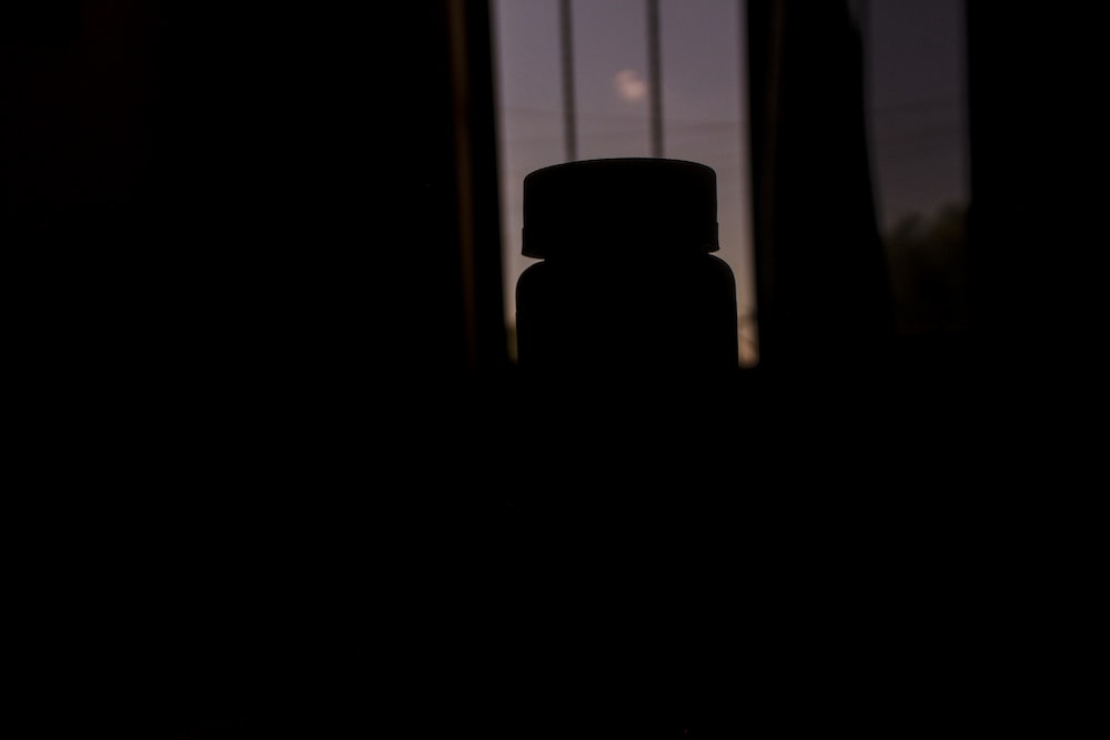 a bottle sitting in front of a window in a dark room