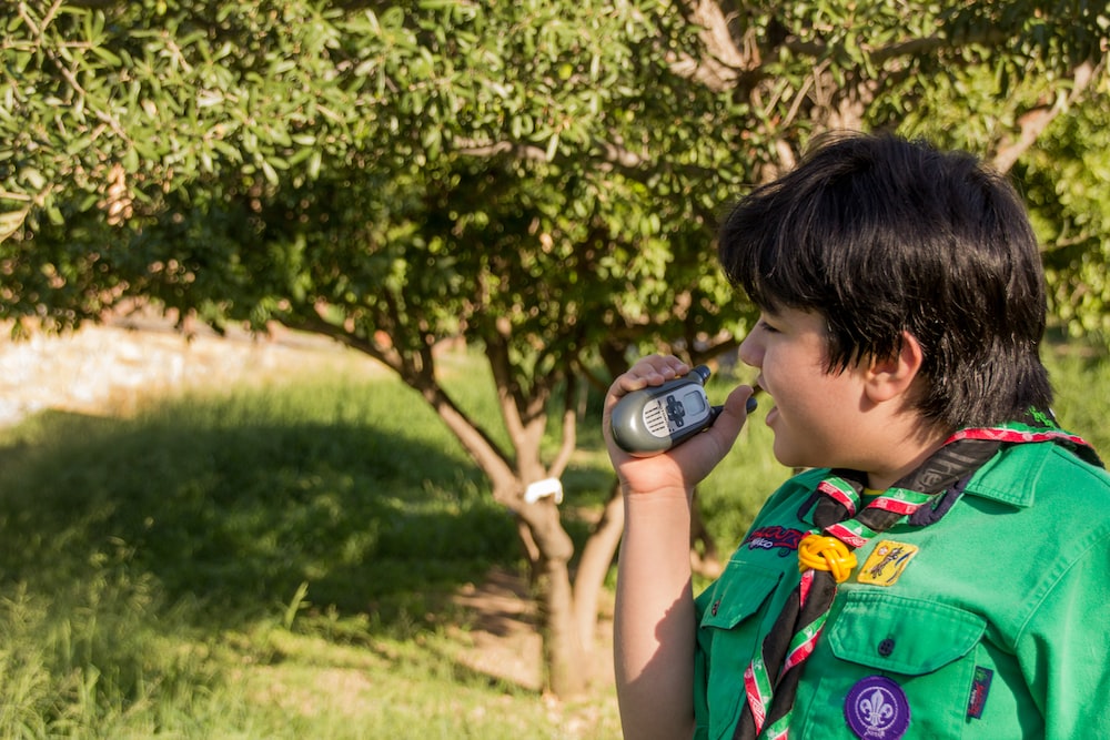 a boy in a green shirt drinking from a bottle
