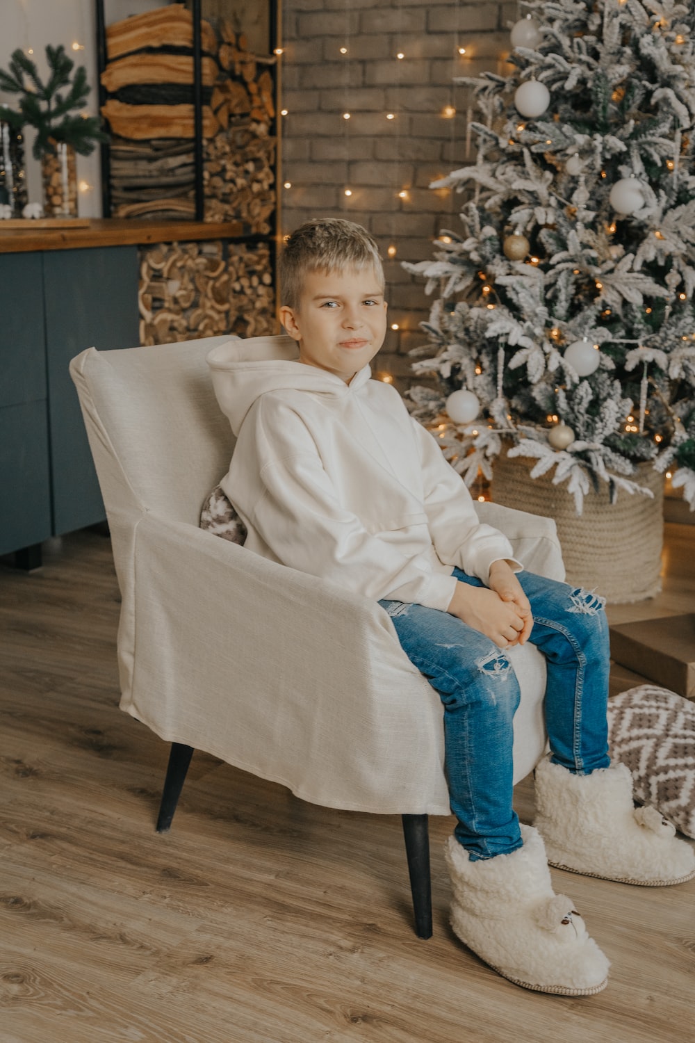 a boy sitting in a chair in front of a christmas tree