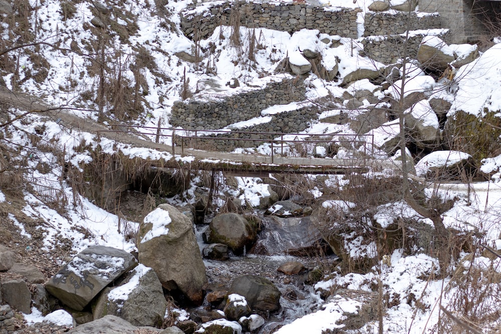 a bridge over a small stream in the snow