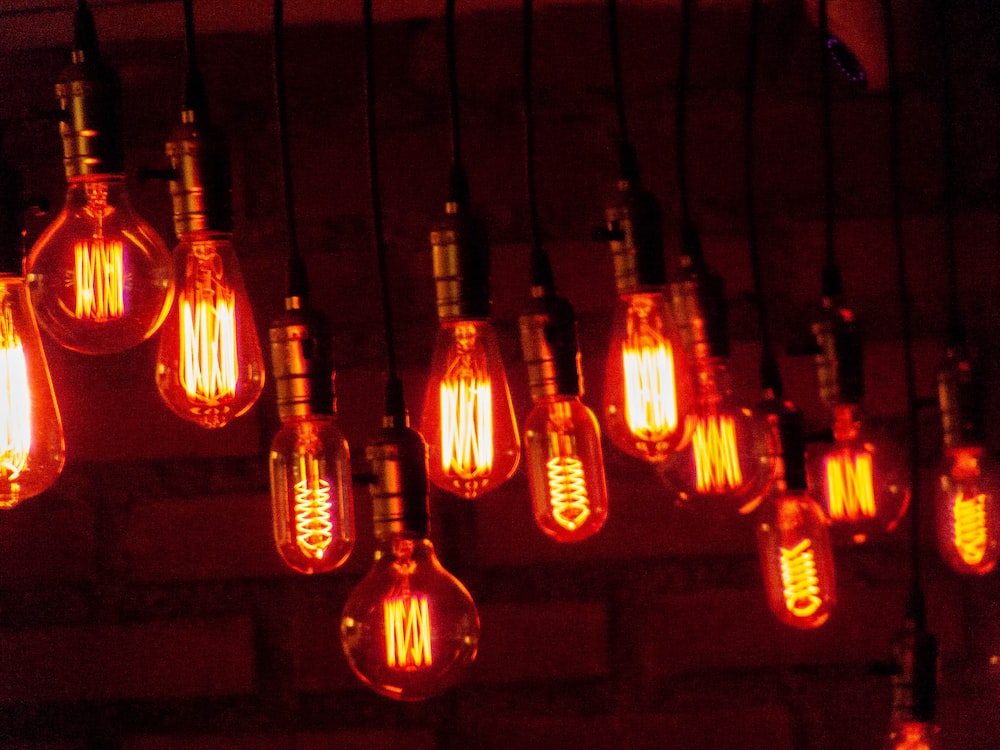 a bunch of light bulbs hanging from a brick wall