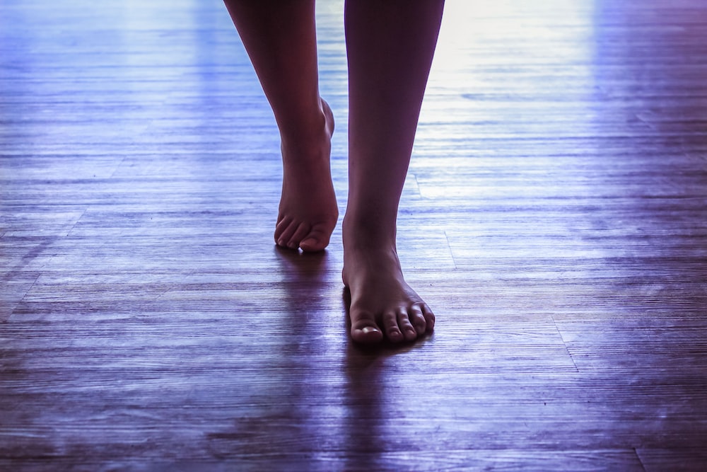 a close up of a person's bare feet on a wooden floor