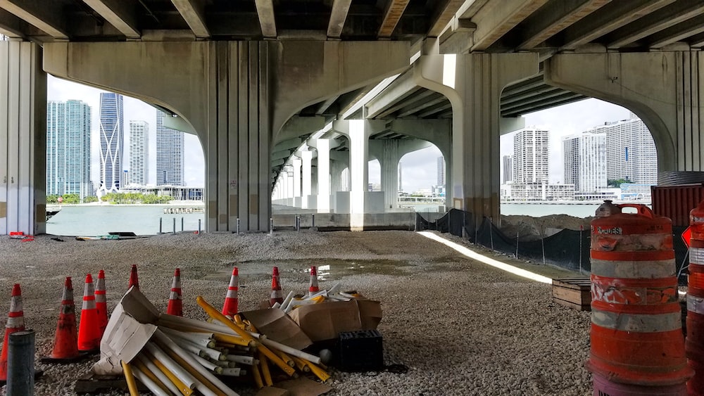 a construction site under a bridge with construction cones on the ground