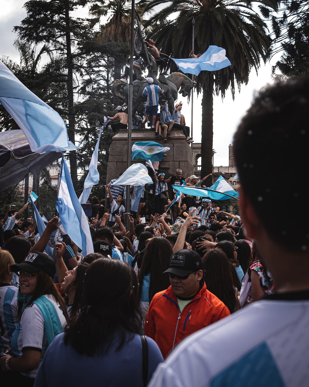 a crowd of people standing around each other holding blue flags