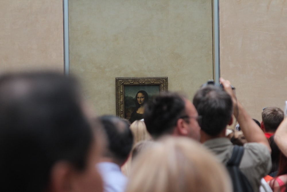 a crowd of people taking pictures of a painting