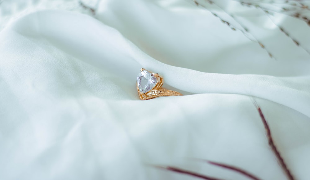a diamond ring sitting on a white sheet