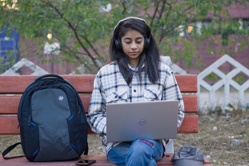 a girl sitting on a bench using a laptop