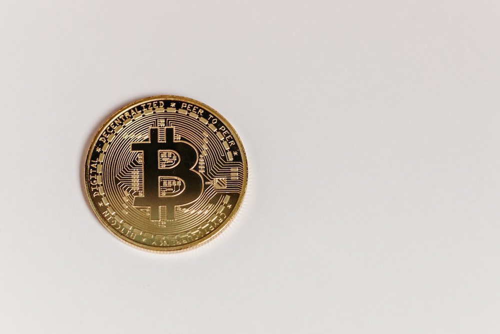 a gold bit coin sitting on top of a white surface