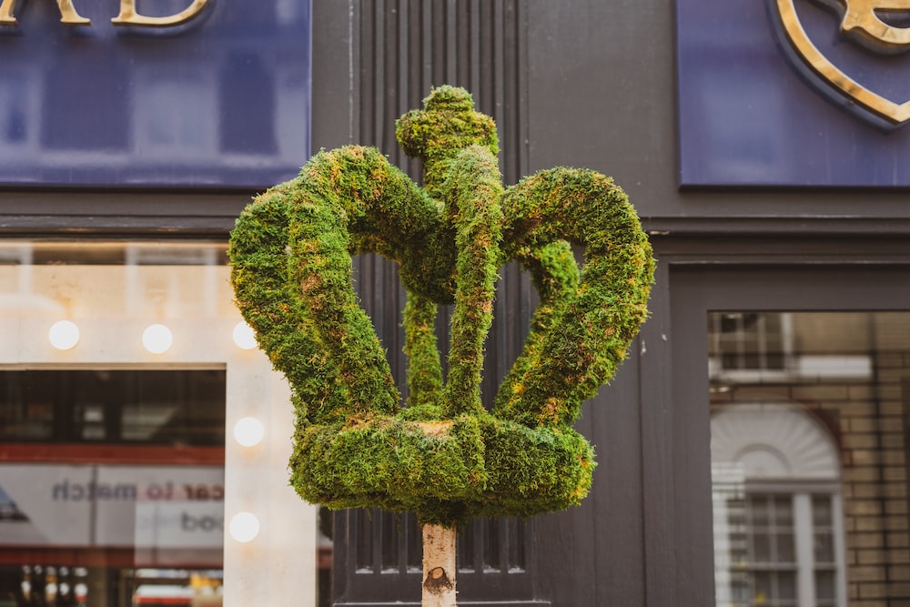 a green sculpture of a flower on a pole in front of a store