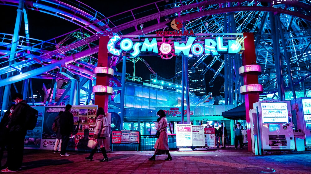 a group of people standing in front of a carnival world sign