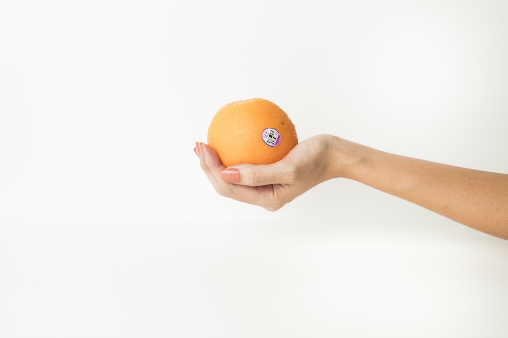 a hand holding an orange