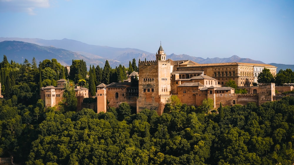 a large building surrounded by trees with Alhambra in the background