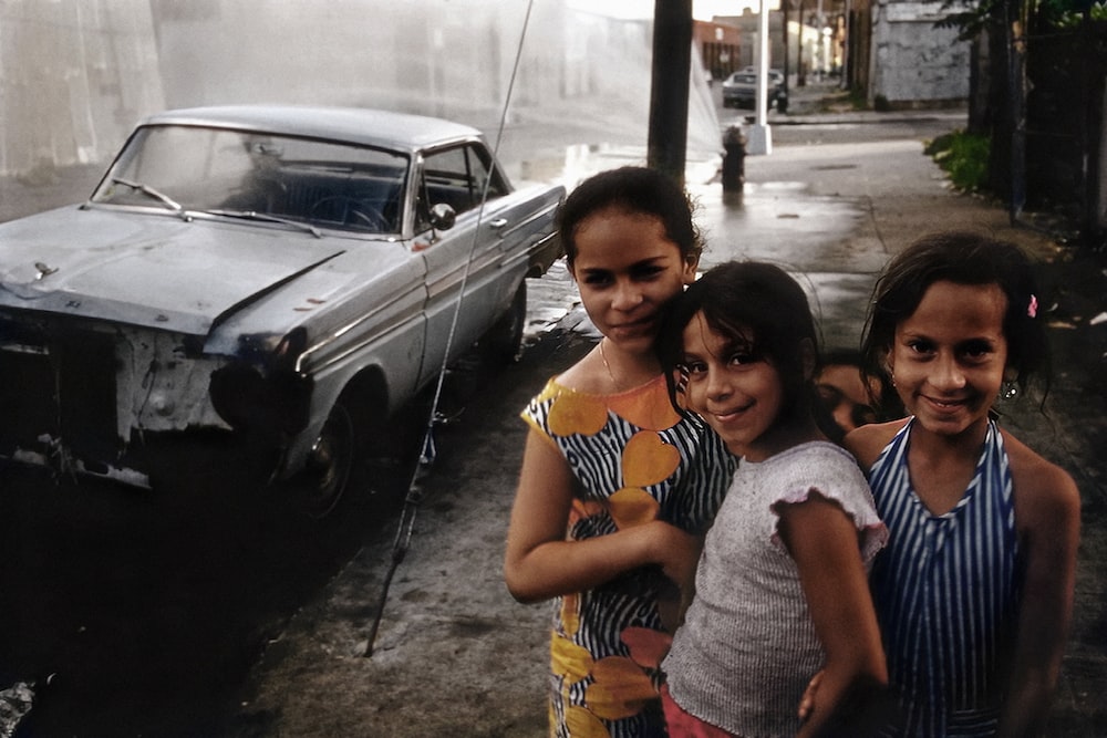a little girl standing in front of a car posing for the camera