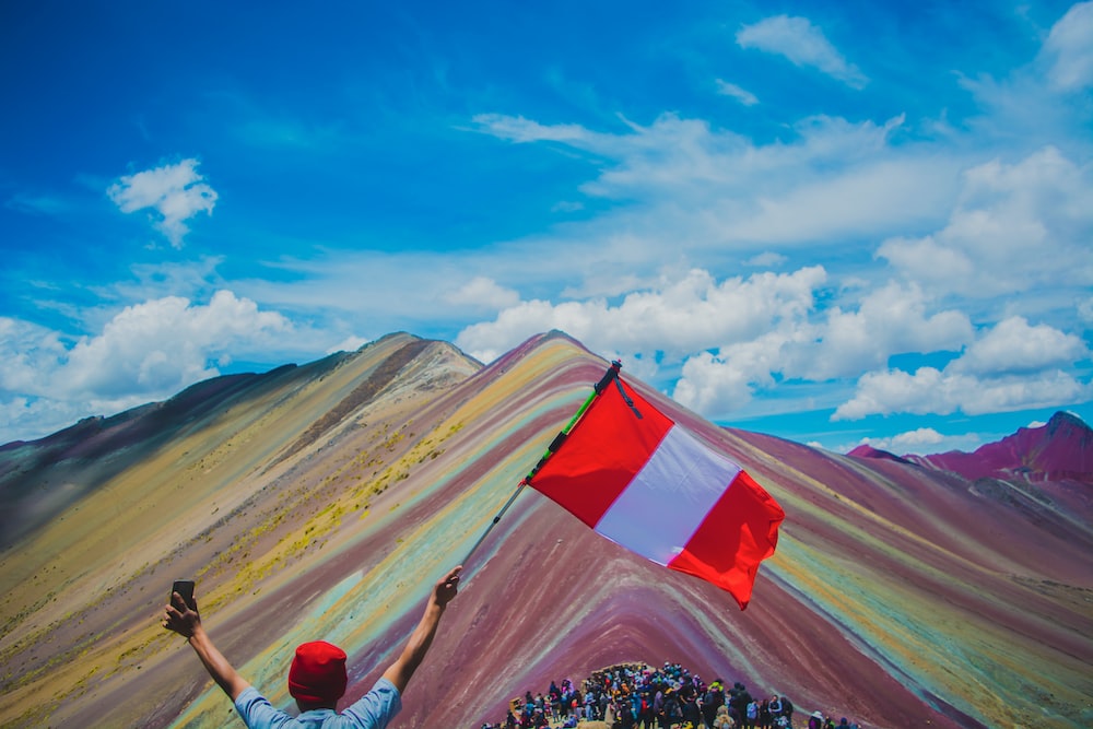 a man holding a flag on top of a mountain