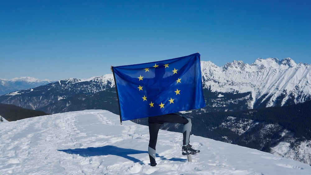 a man holding a flag on top of a snow covered mountain