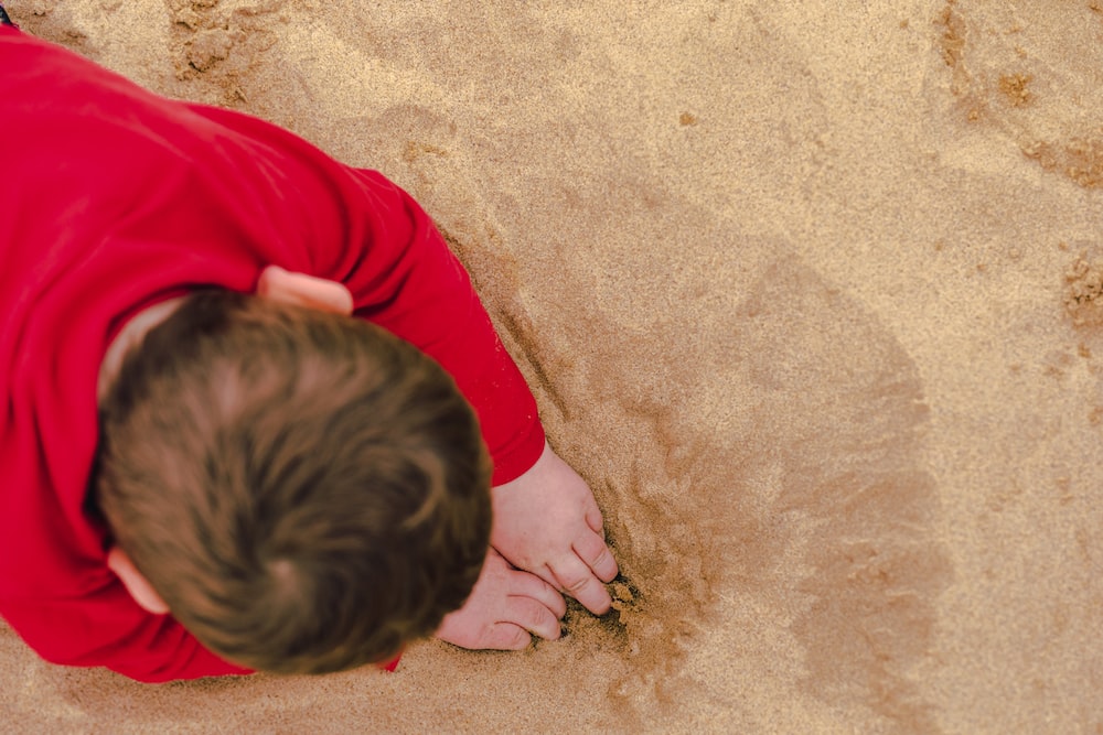 a man in a red shirt laying in the sand