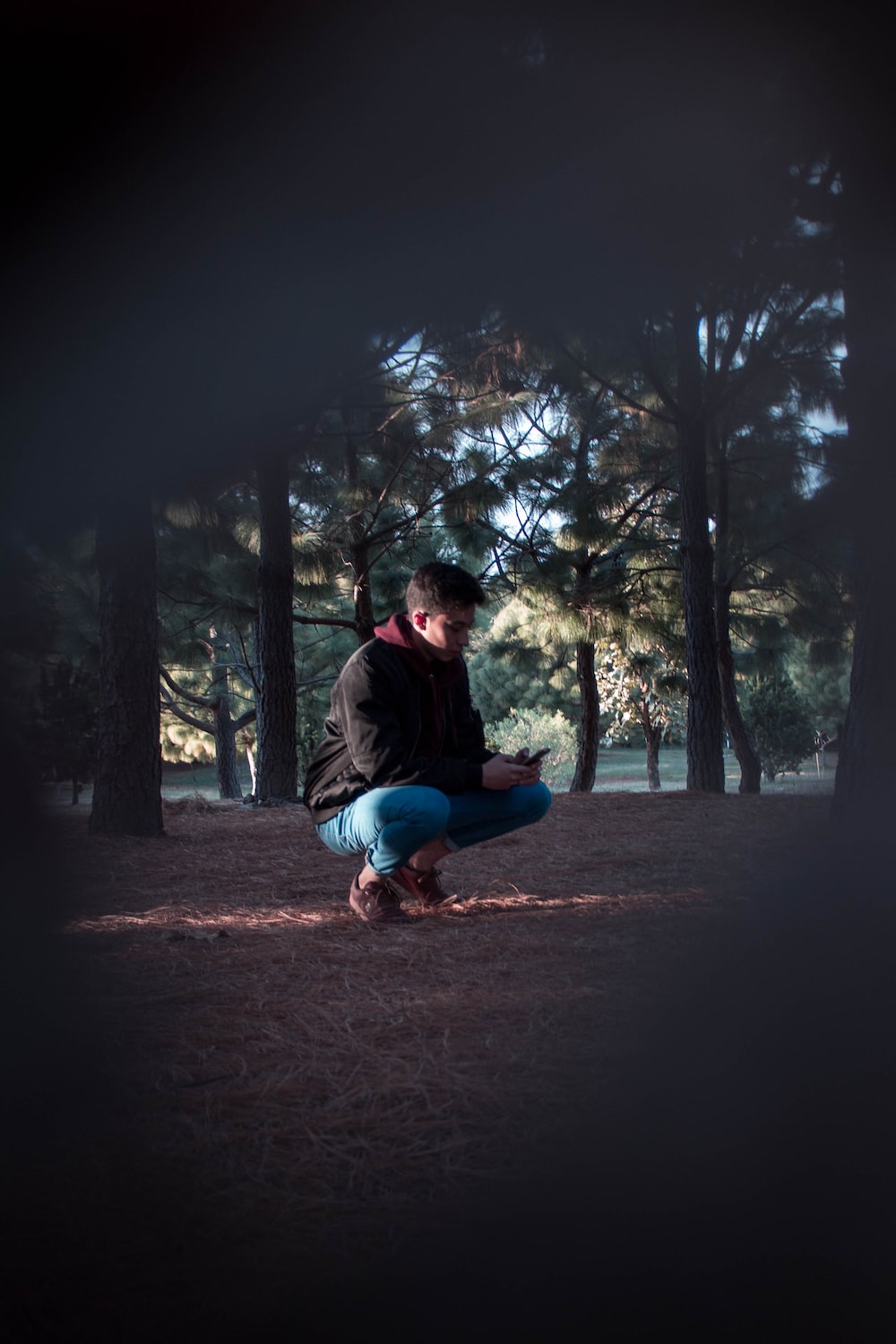 a man squatting down in the middle of a forest