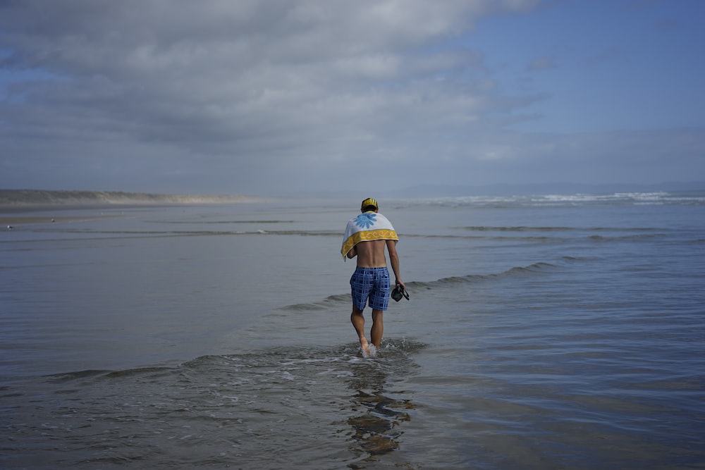 a man walking into the ocean with a surfboard