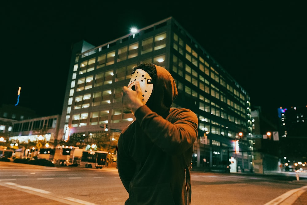 a man wearing a mask is standing on the street