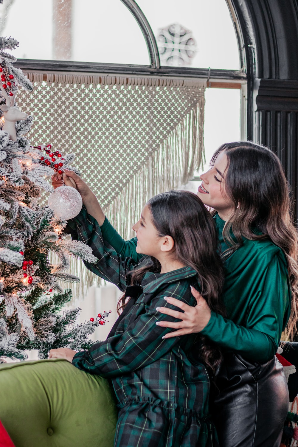 a mother and daughter decorating a christmas tree