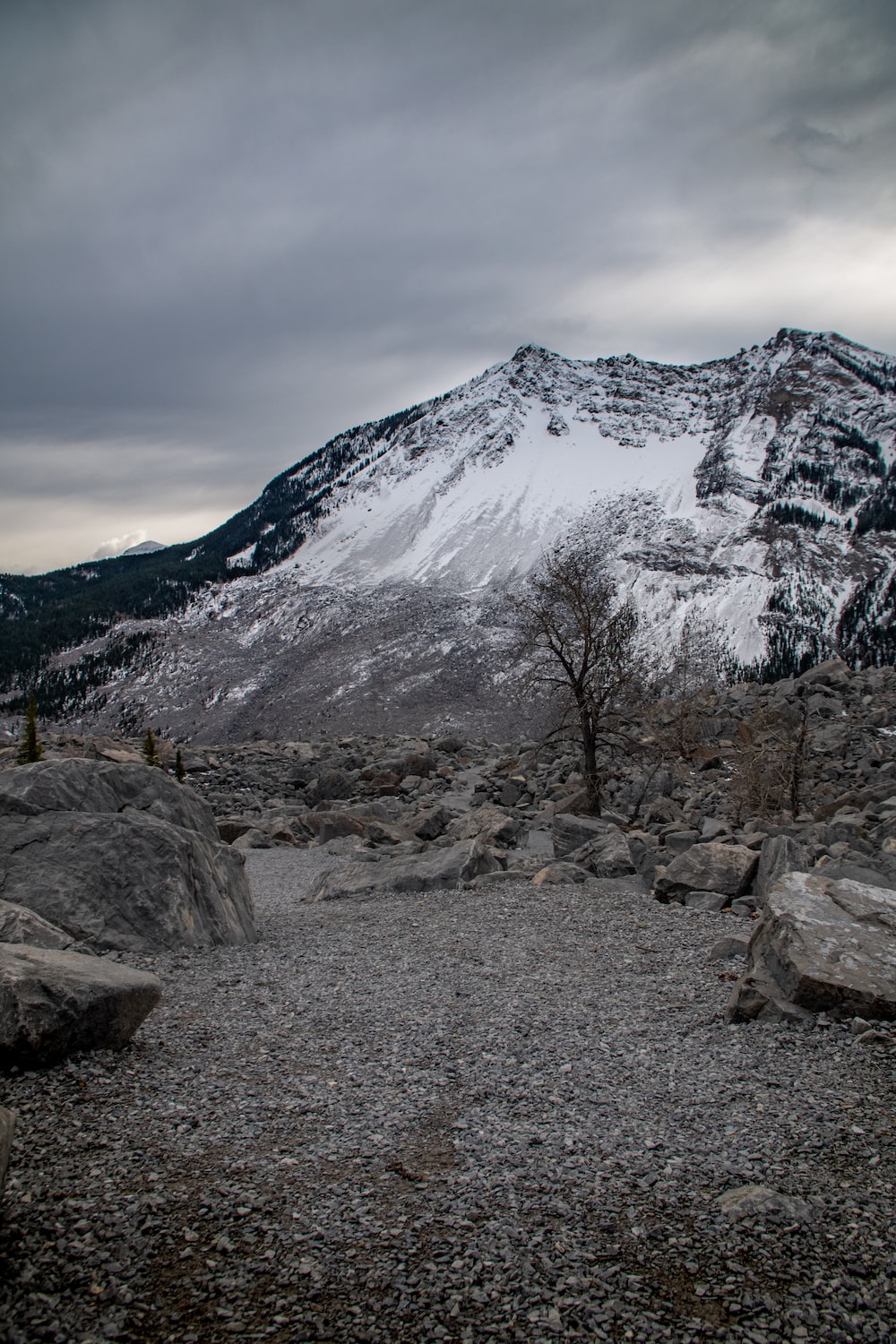 a mountain covered in snow and rocks under a cloudy sky