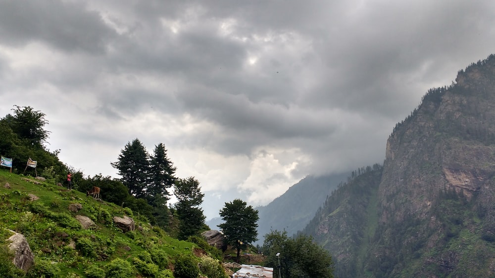 a mountain side road with a cloudy sky in the background