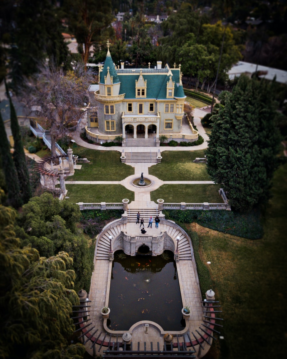 an aerial view of a mansion with a pond