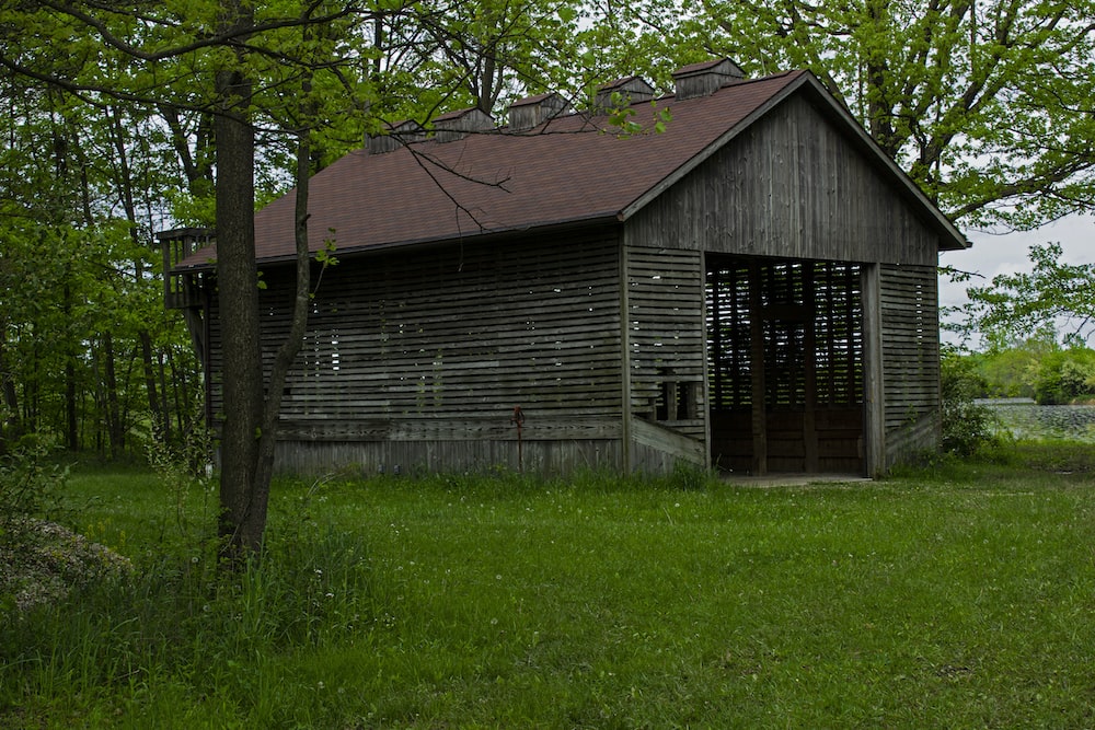 an old wooden building sitting in the middle of a field