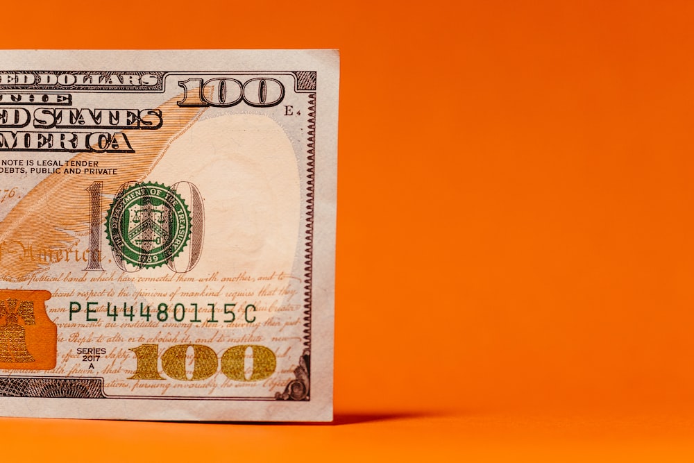 a one hundred dollar bill on an orange background