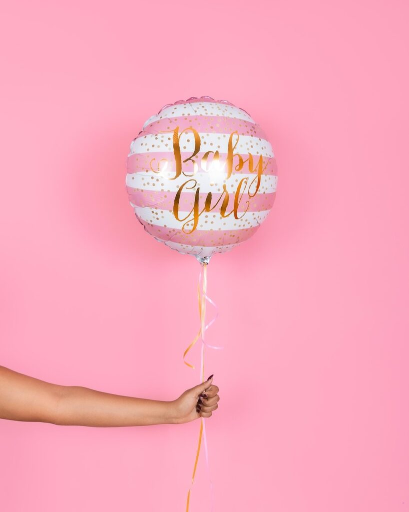 a person holding a balloon that says baby girl