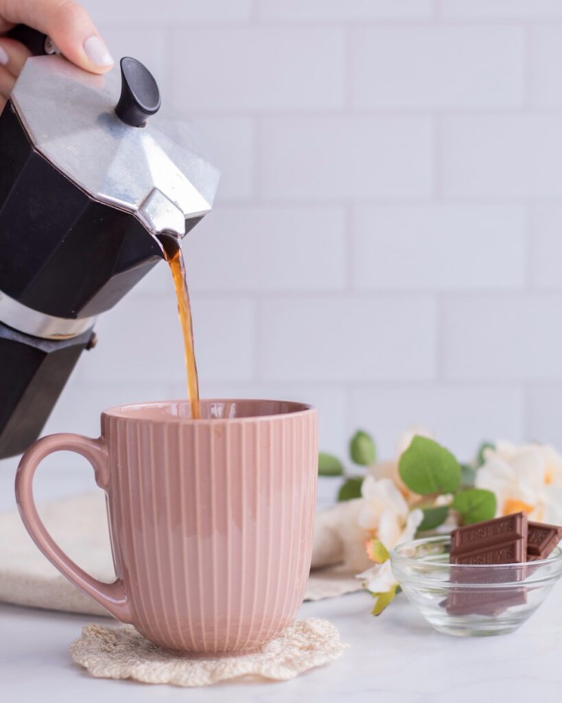 a person pours coffee into a pink mug