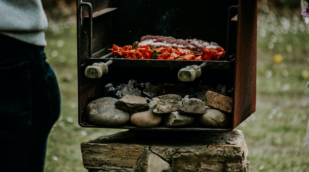 a person standing next to a grill with food on it
