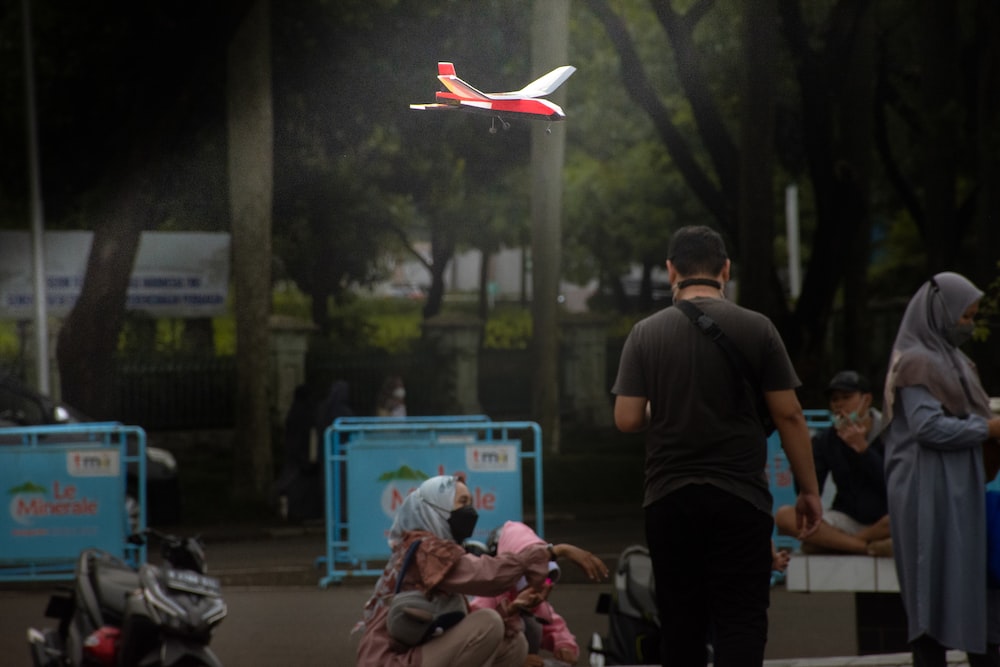 a person standing next to a person lying on the ground with a drone flying in the air