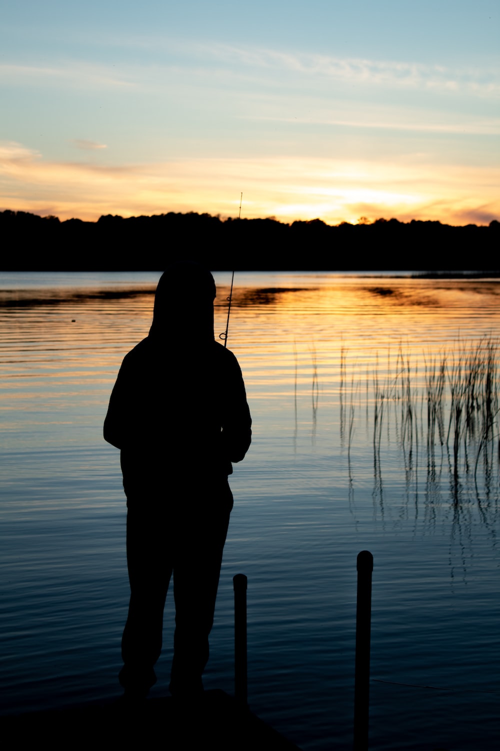 a person standing on a dock with a fishing rod