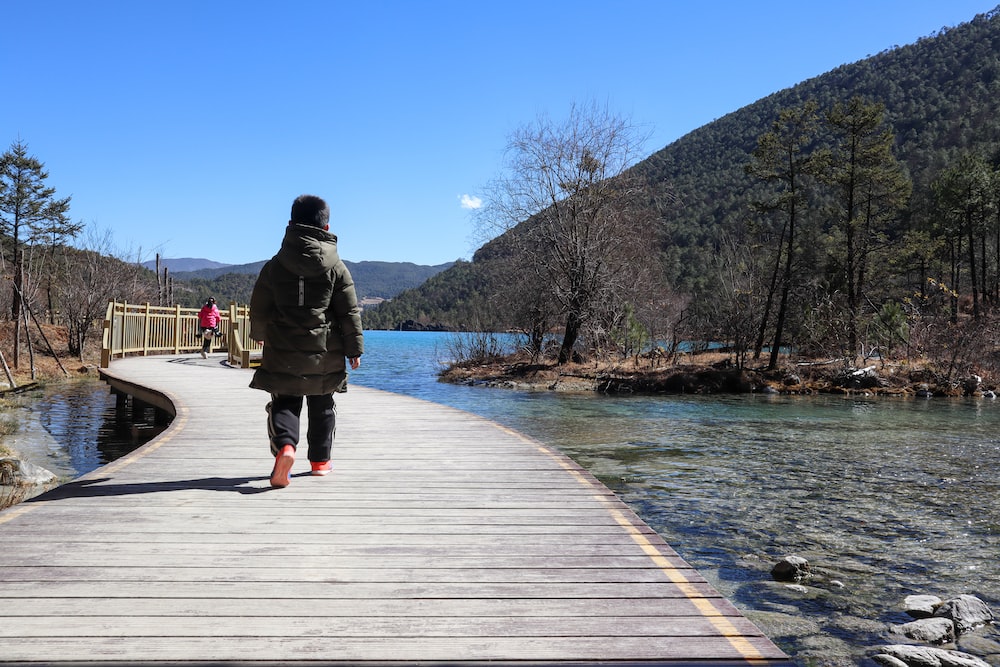 a person walking across a wooden bridge over a body of water