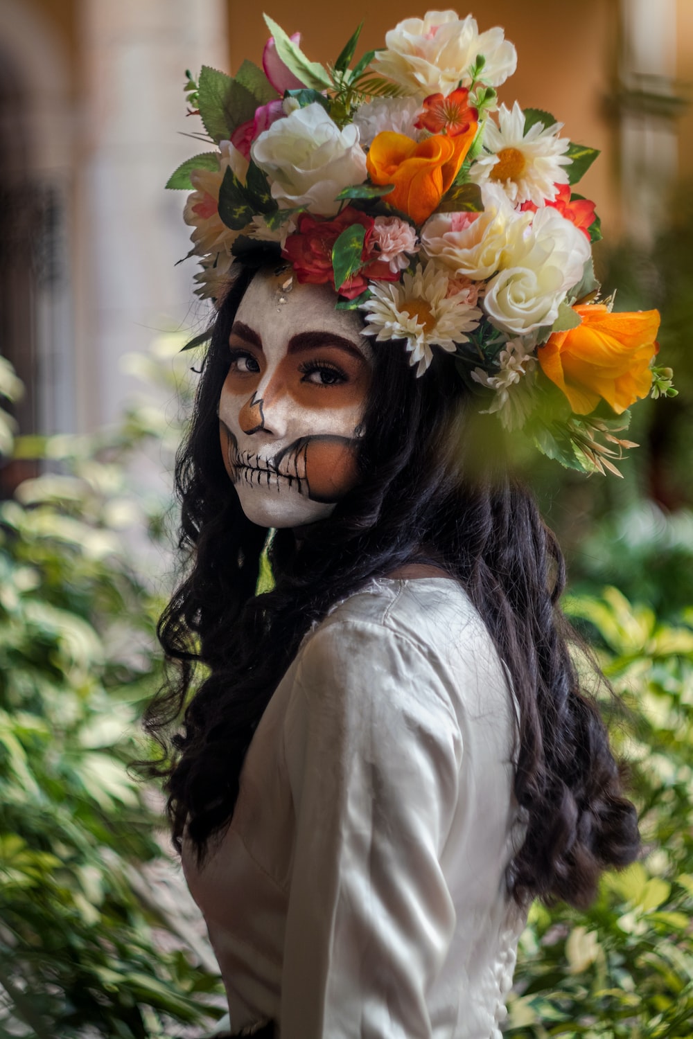 a person with a mask and flowers on their head