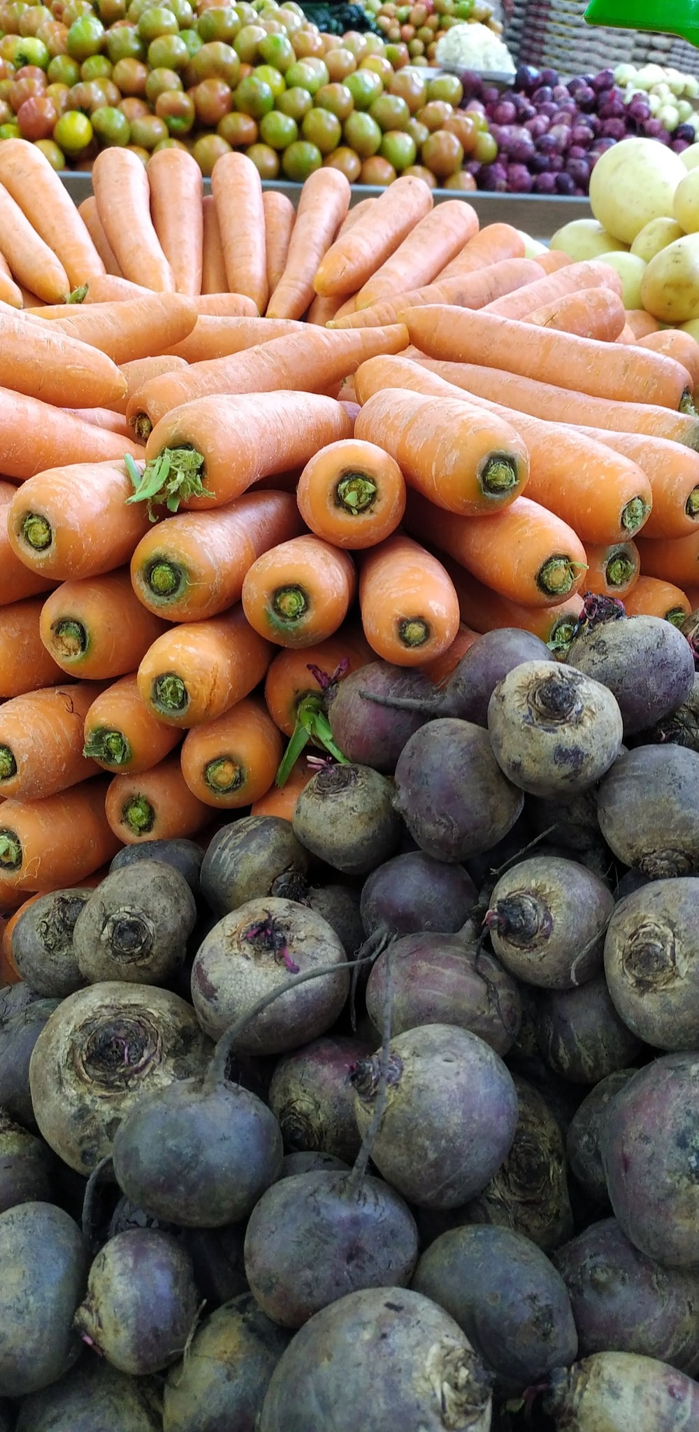 a pile of carrots sitting next to other fruits and vegetables
