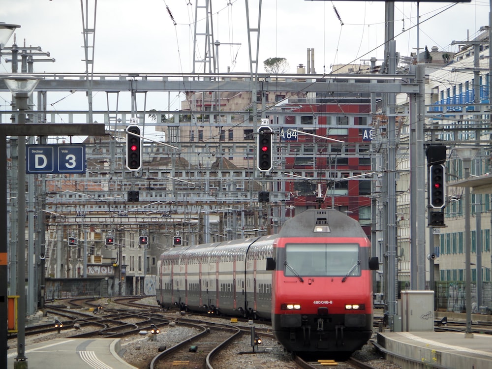 a red train traveling down train tracks next to tall buildings