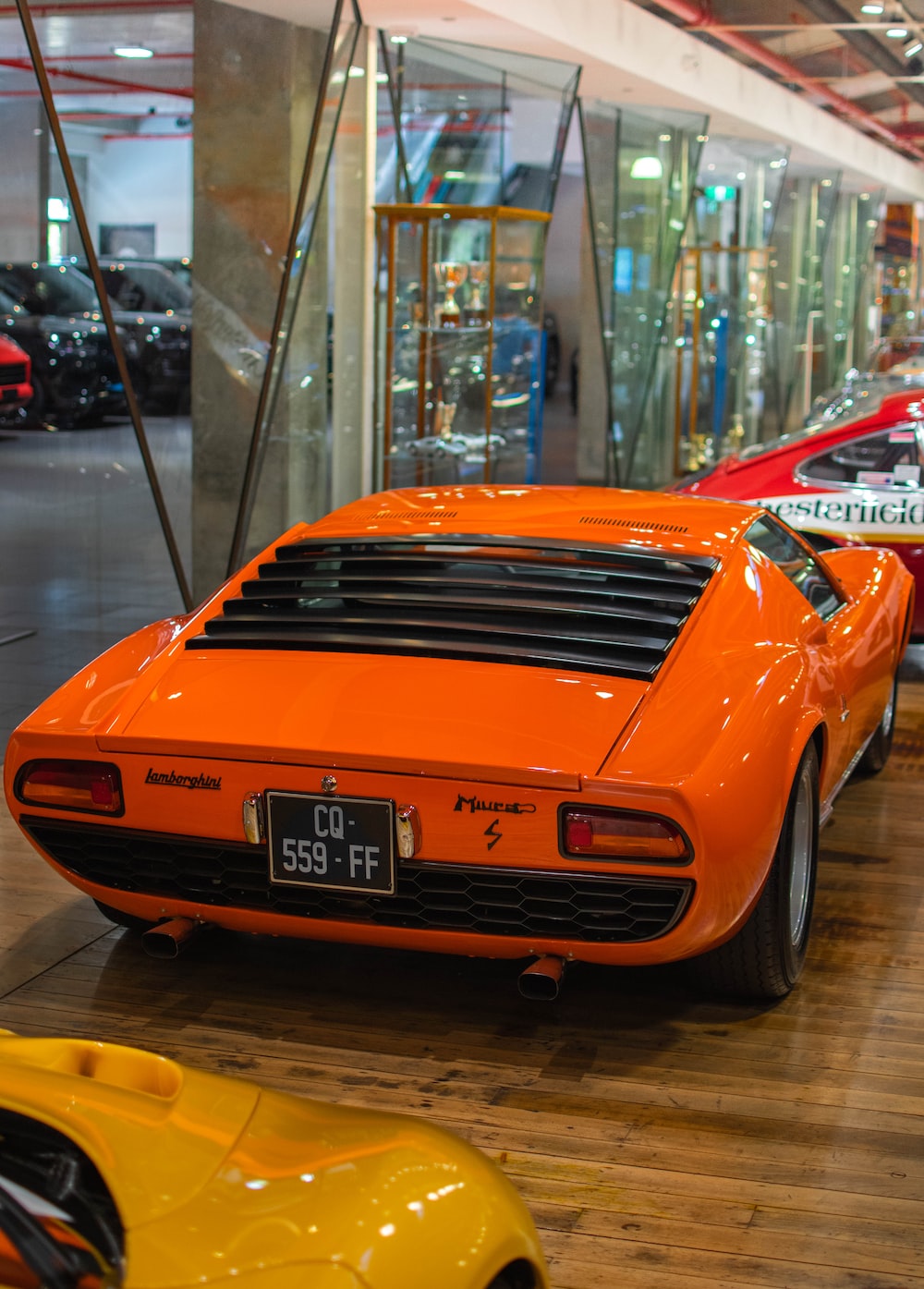 a row of orange sports cars in a showroom