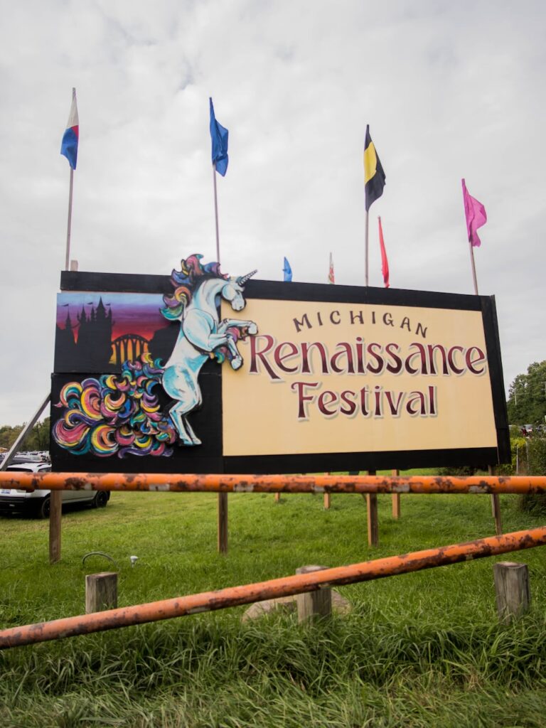 a sign for a renaissance festival in a field