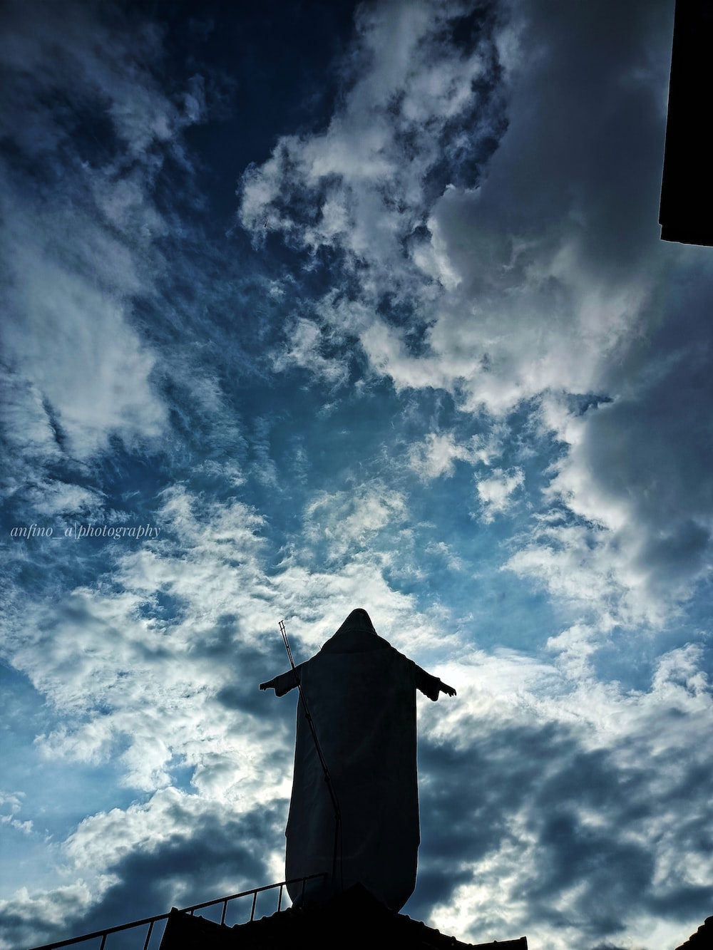 a statue is silhouetted against a cloudy sky