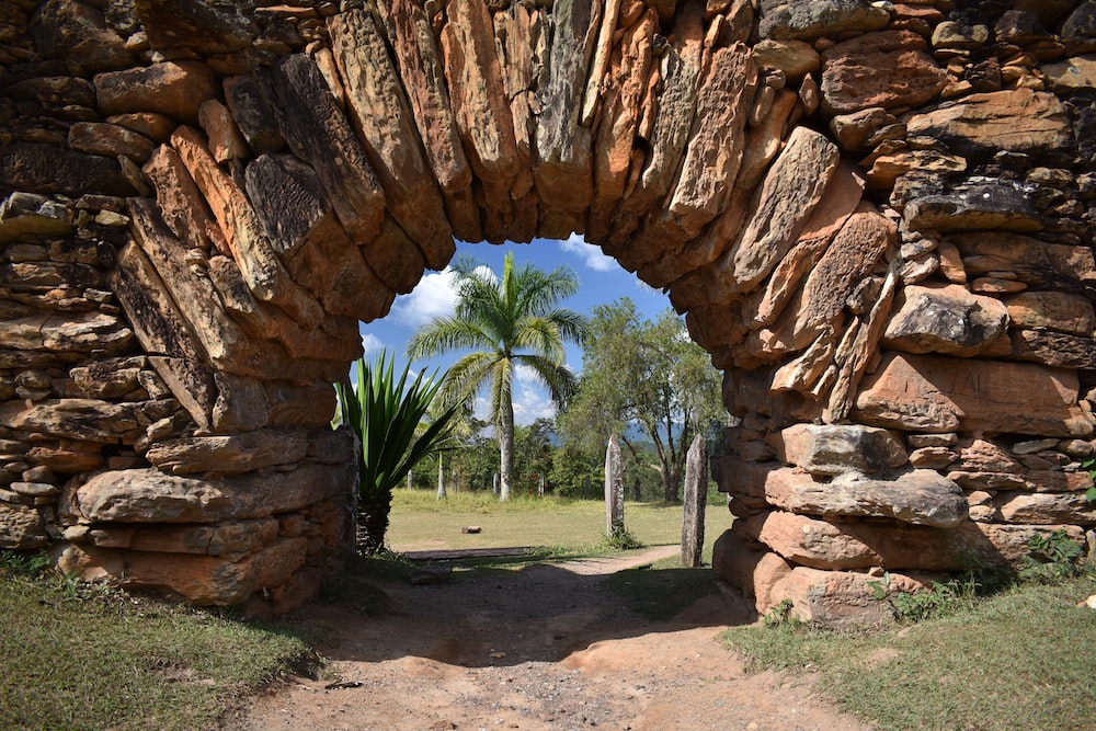 a stone archway with trees and grass