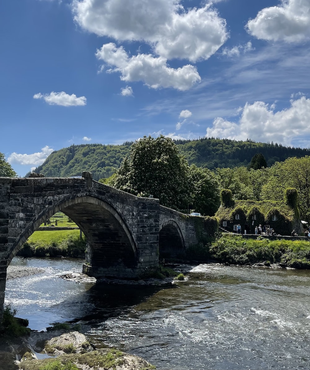 a stone bridge over a river surrounded by mountains