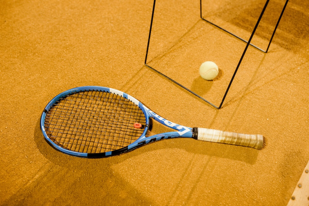 a tennis racket and ball on the ground